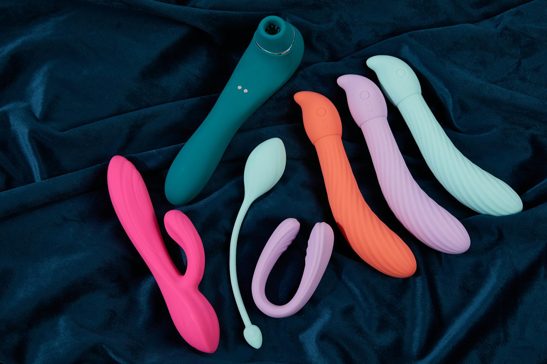 Vibratore rosa su sfondo viola con coriandoli a forma di cuore e candele accese