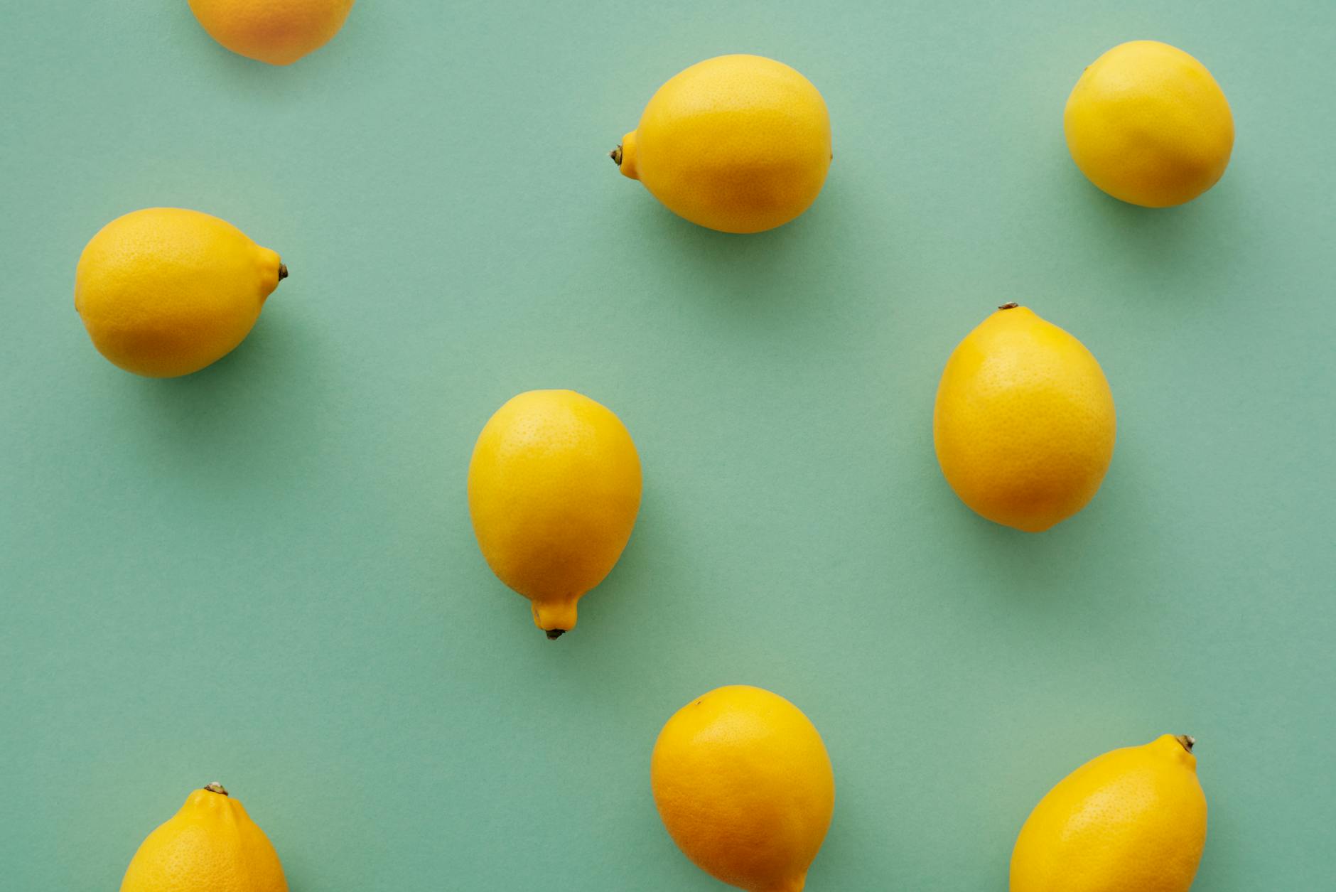 Limoni gialli brillanti disposti su sfondo verde pastello, che rappresentano il risveglio e il rinnovamento del piacere
