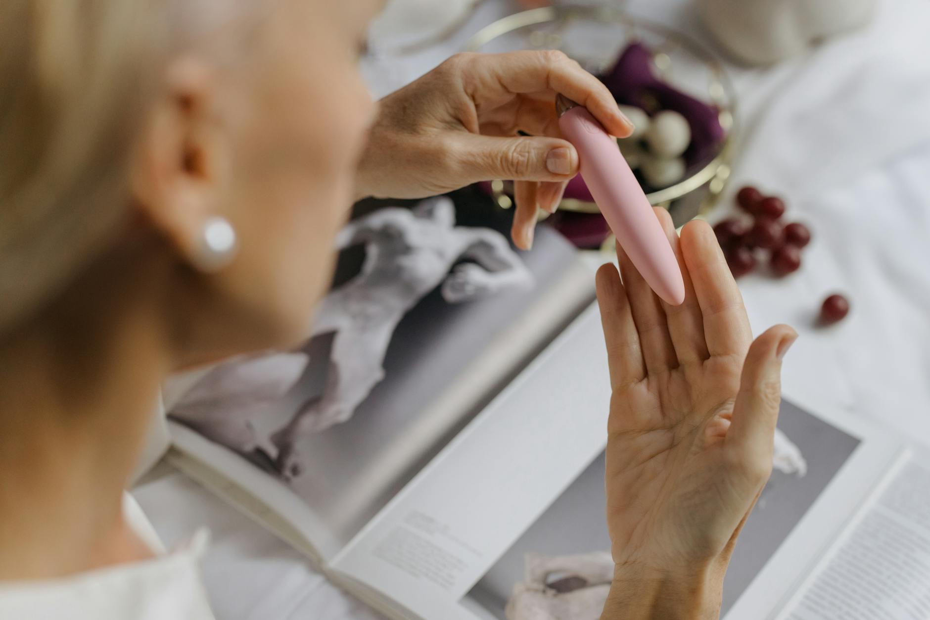 Donna con occhiali che tiene in mano vibratori blu e rosa in maniera consapevole