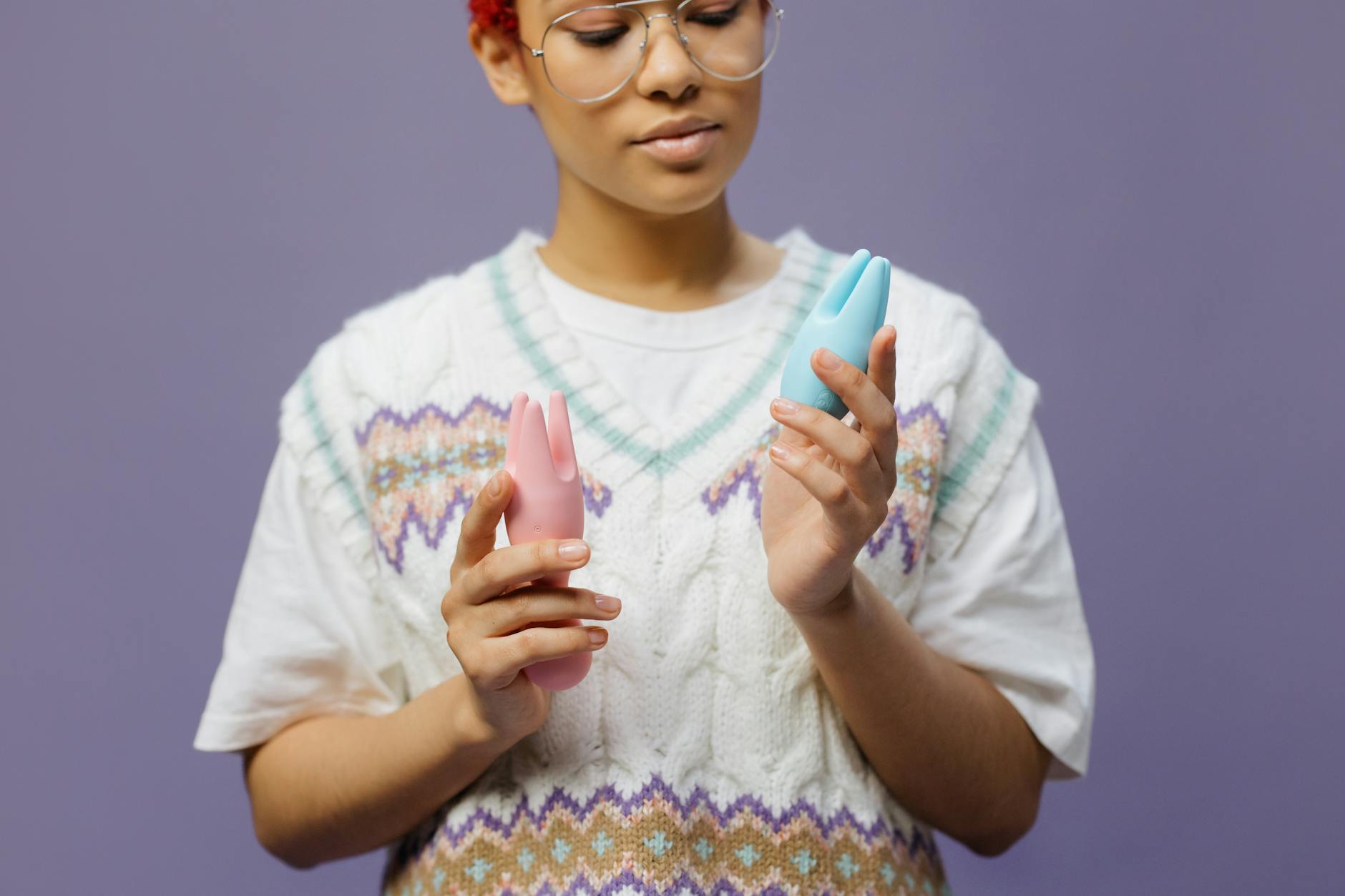 Donna che tiene in mano un vibratore blu e rosa in un momento di riflessione personale